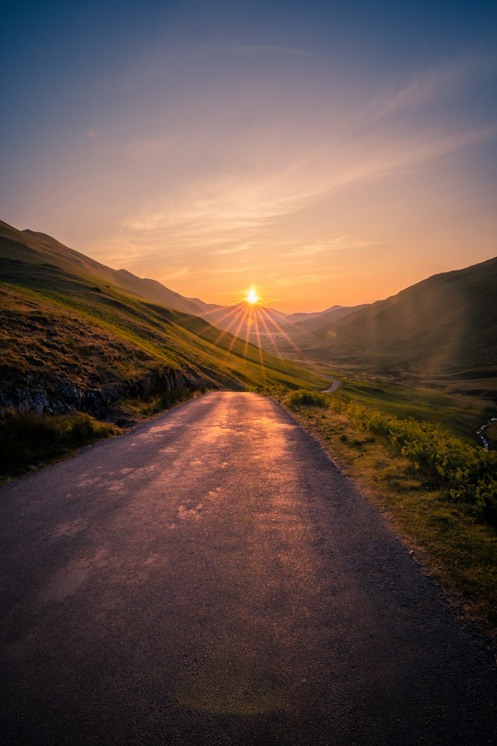 the sun is setting over a mountain road