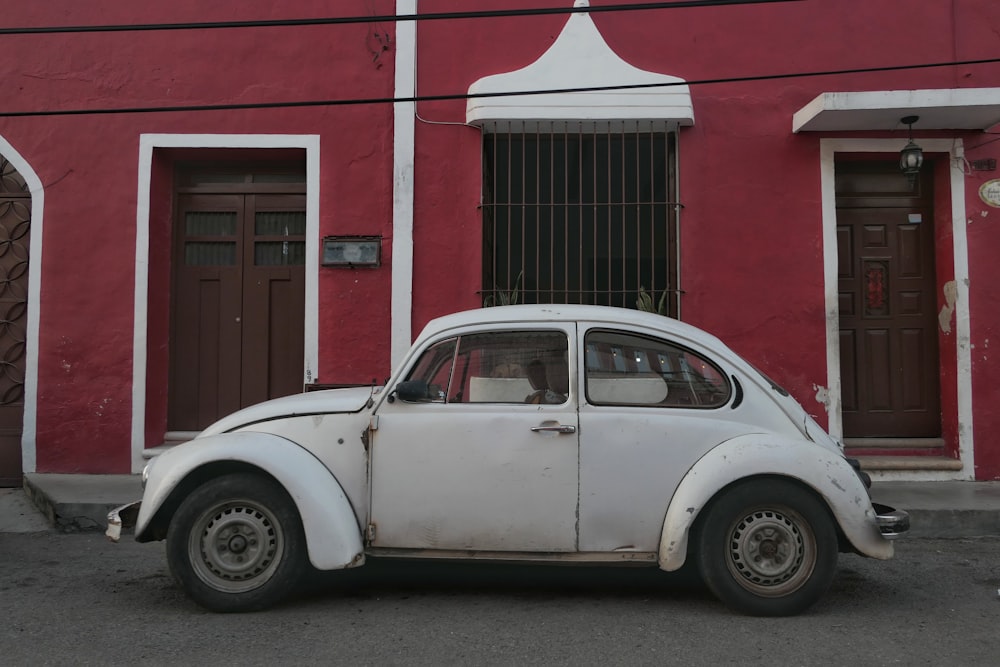 a white car parked in front of a red building