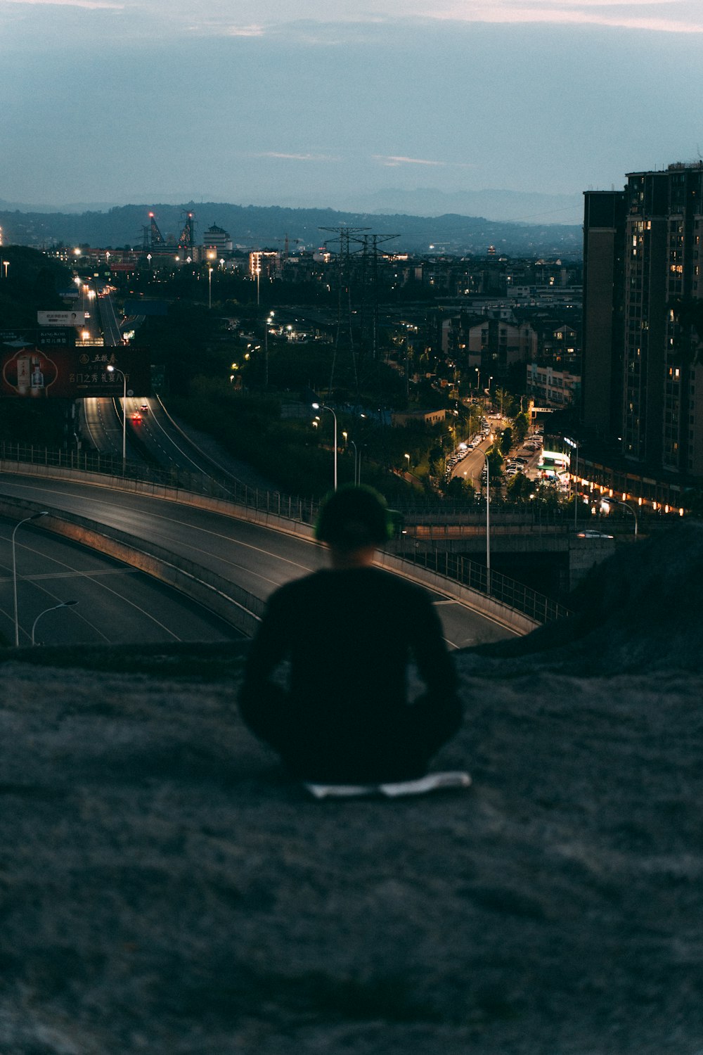 a man sitting on top of a rock next to a highway