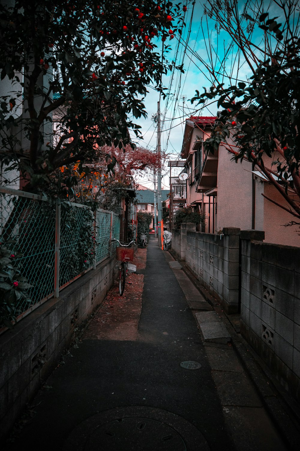 a narrow street with a fence and a red chair