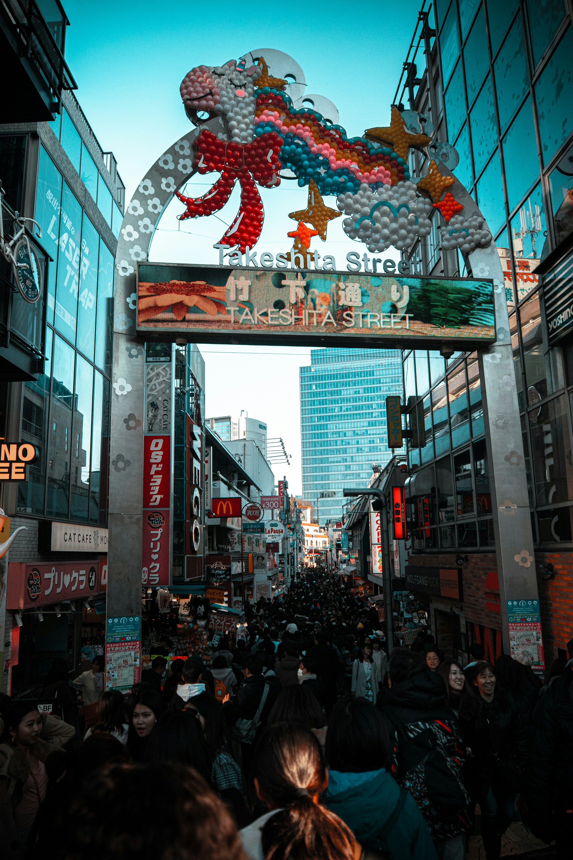 Una multitud de personas caminando por una calle junto a edificios altos
