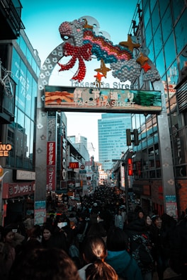 a crowd of people walking down a street next to tall buildings