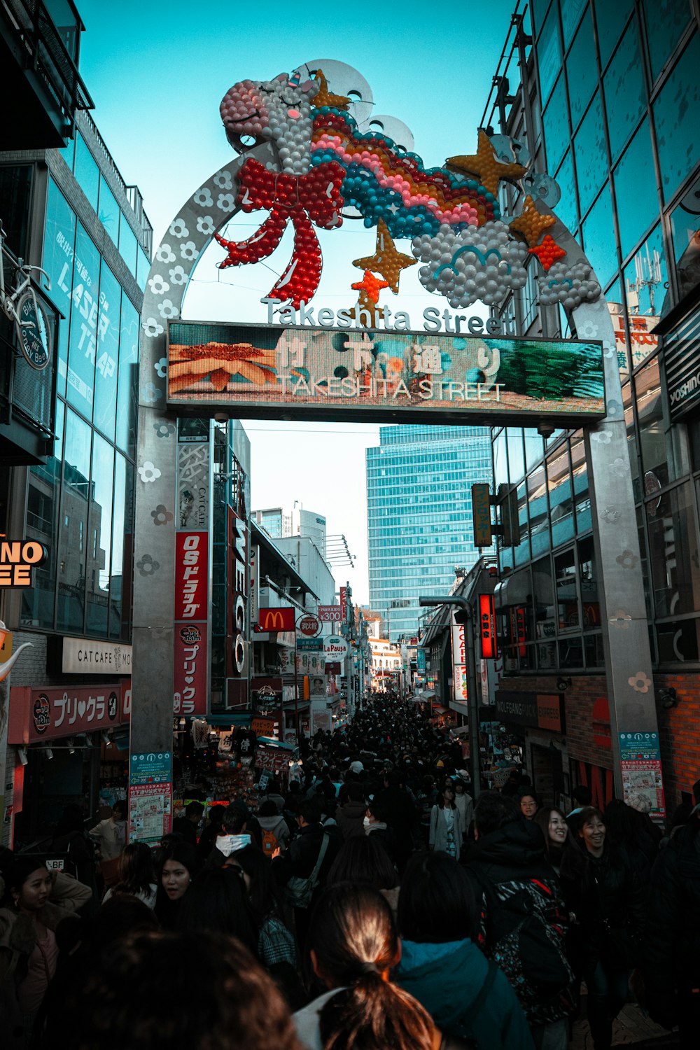 a crowd of people walking down a street next to tall buildings