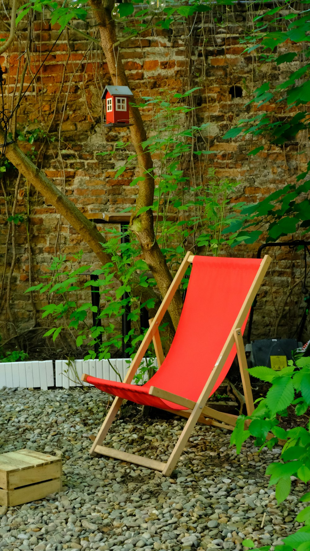 Una sedia da giardino rossa seduta in cima a un campo di ghiaia