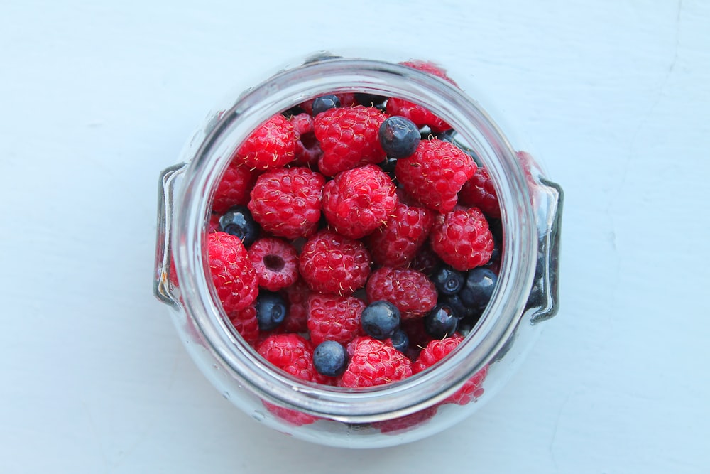 a jar filled with raspberries and blueberries