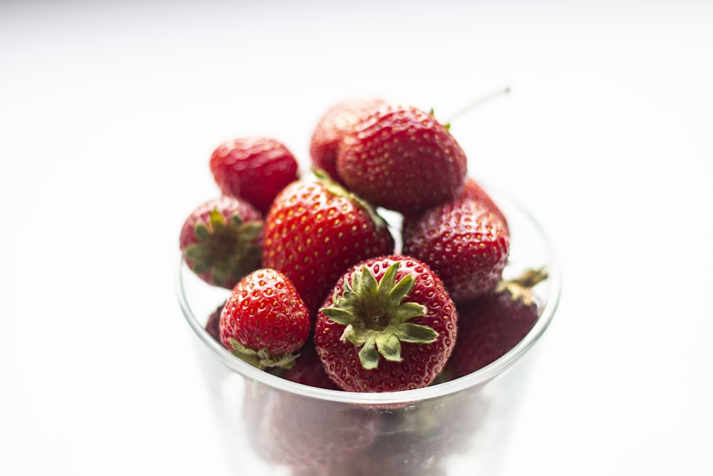 a bowl of strawberries on a white surface