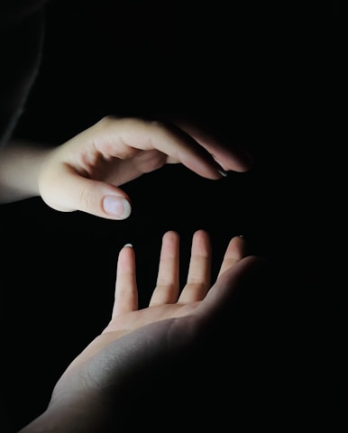 Hands gently hovering over a glowing chakra chart during a Reiki session.