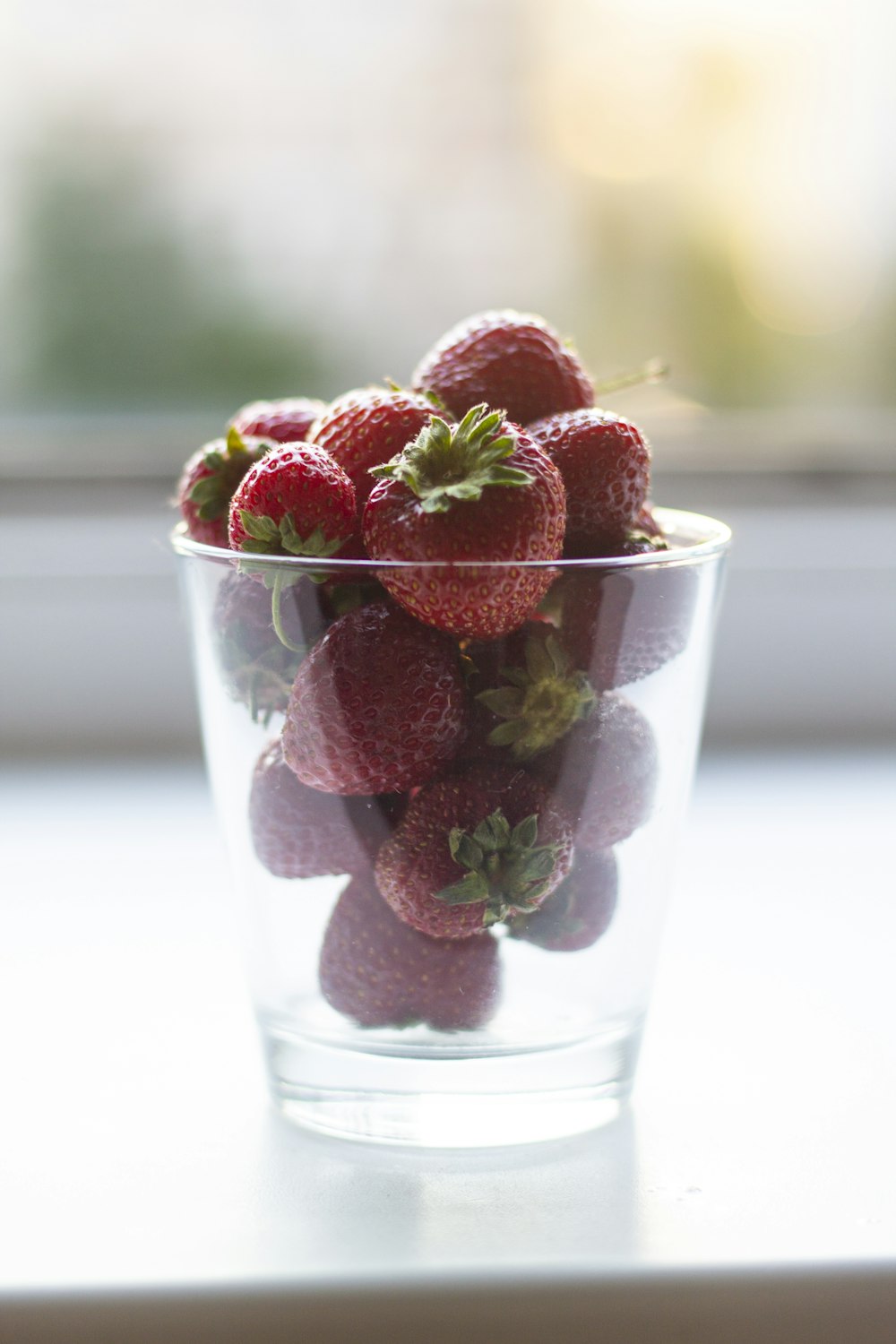 a glass filled with lots of strawberries on top of a table