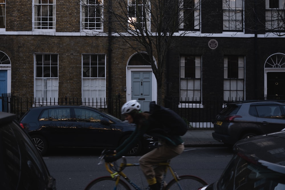 a man riding a bike down a street next to parked cars