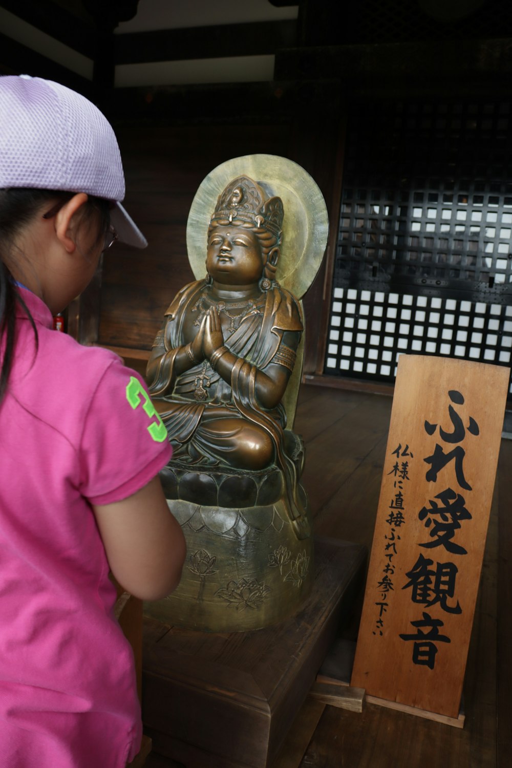 a little girl looking at a statue of buddha