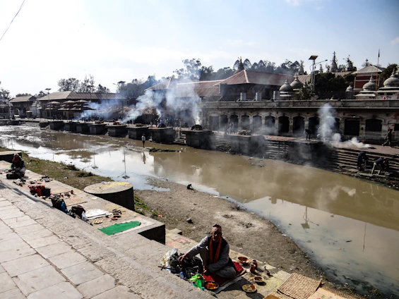 A serene view of the Ganges river at sunrise with pilgrims performing poja rituals on the ghats.