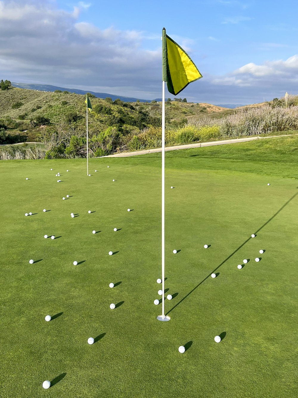 a golf course with a yellow flag and white balls