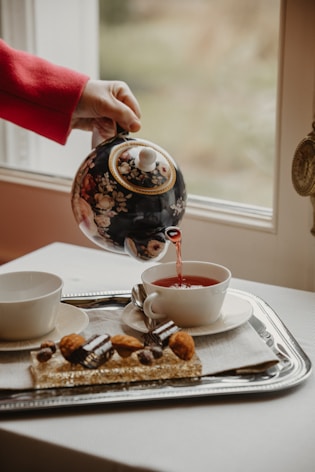 a person pouring tea into a cup on a tray