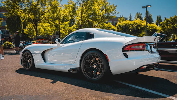 A pristine white sports car gleaming under natural sunlight after a detailed hand wash and wax.
