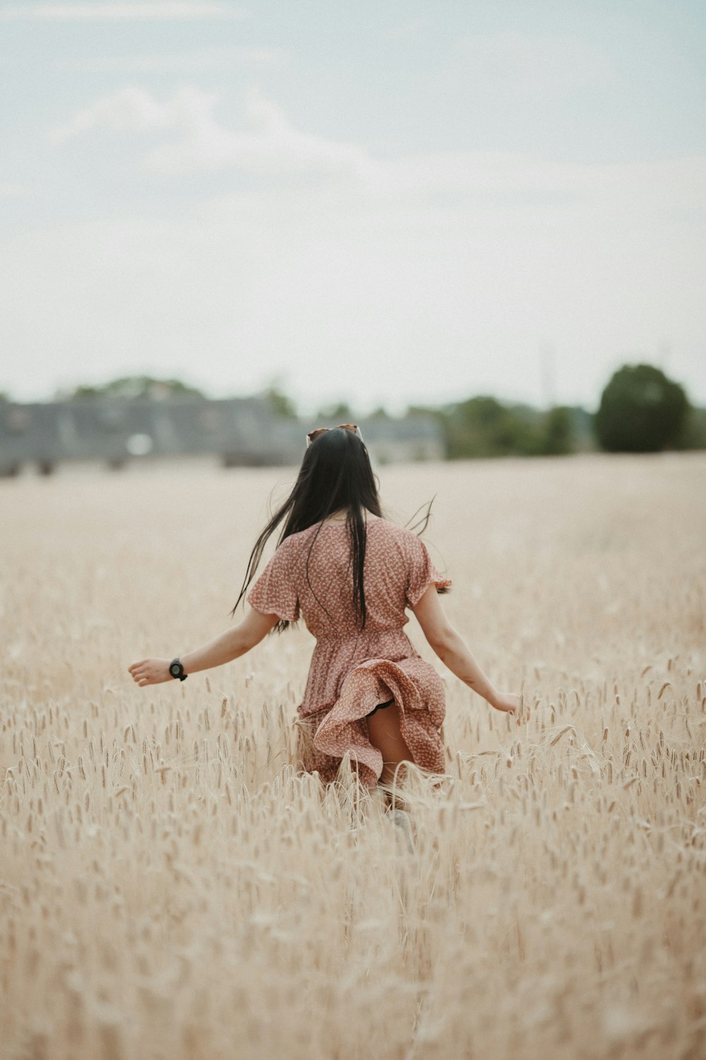 a young girl running through a field of wheat