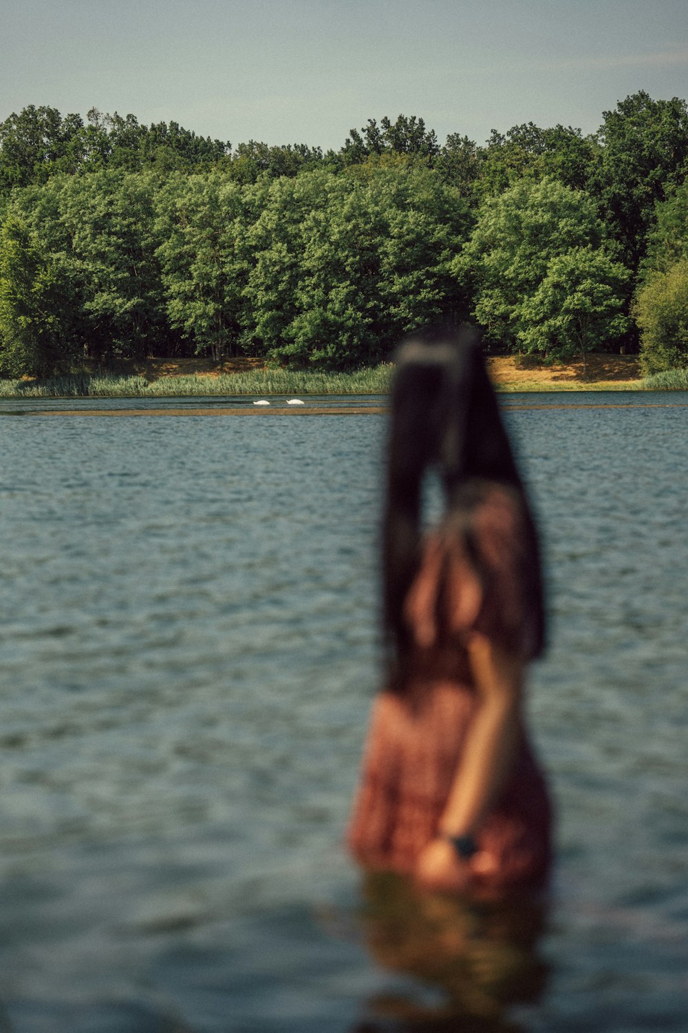 a woman standing in the water looking at a boat