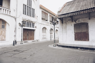 A quiet street corner in Singapore bathed in soft morning light, reflecting faded signs and textured walls.