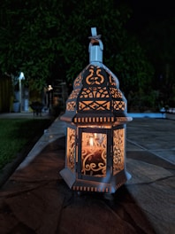 Metal hanging garden lantern glowing warmly in a twilight garden setting
