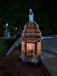 Elegant metal hanging garden lantern glowing softly in a twilight garden setting.