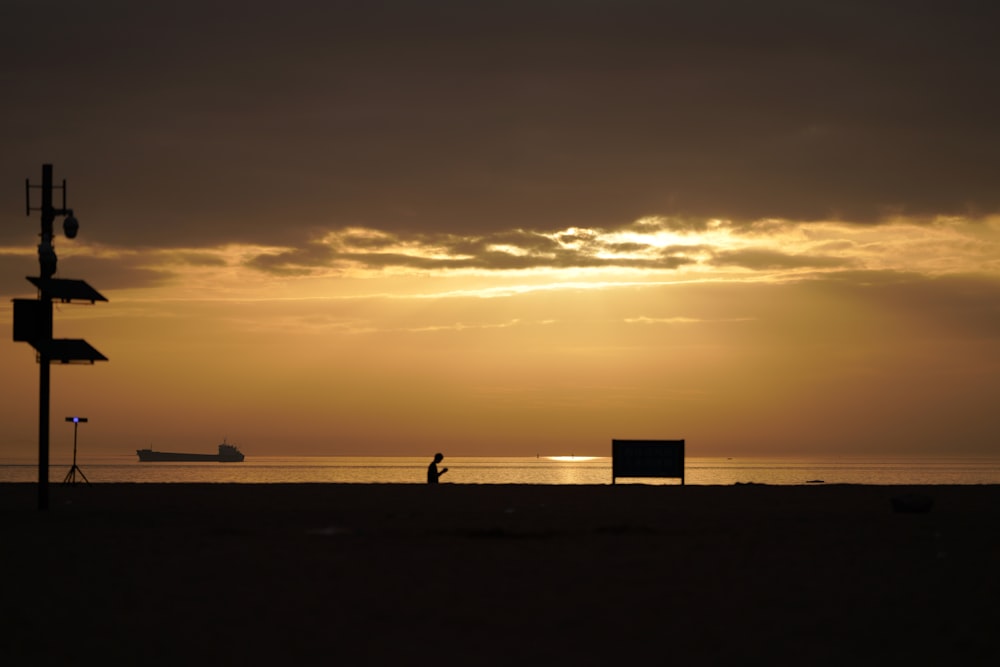 a person walking on a beach at sunset