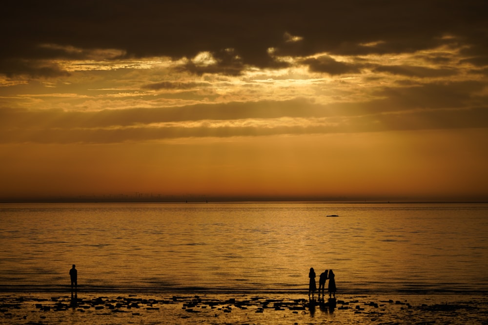 a couple of people standing on top of a beach under a cloudy sky