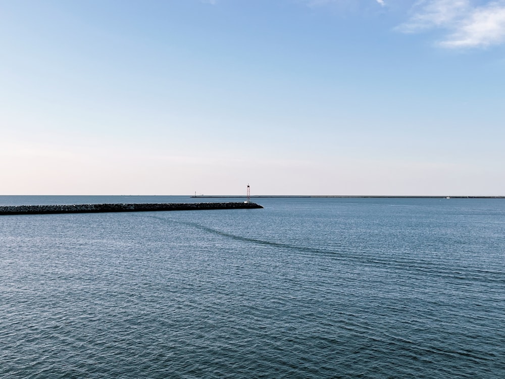 a large body of water sitting under a blue sky