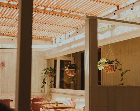A cozy outdoor seating area framed by elegant wooden garden structures under soft natural light.