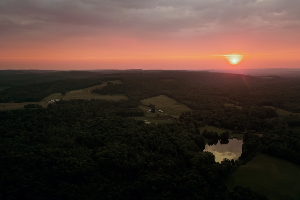 the sun is setting over a field with trees