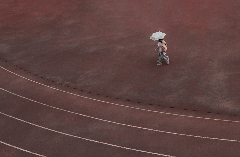 a person with an umbrella walking on a track