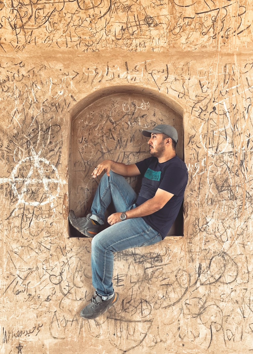a man sitting in a window with graffiti all over it