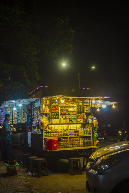 Brightly lit mobile food stand with staff serving happy customers at a bustling outdoor event