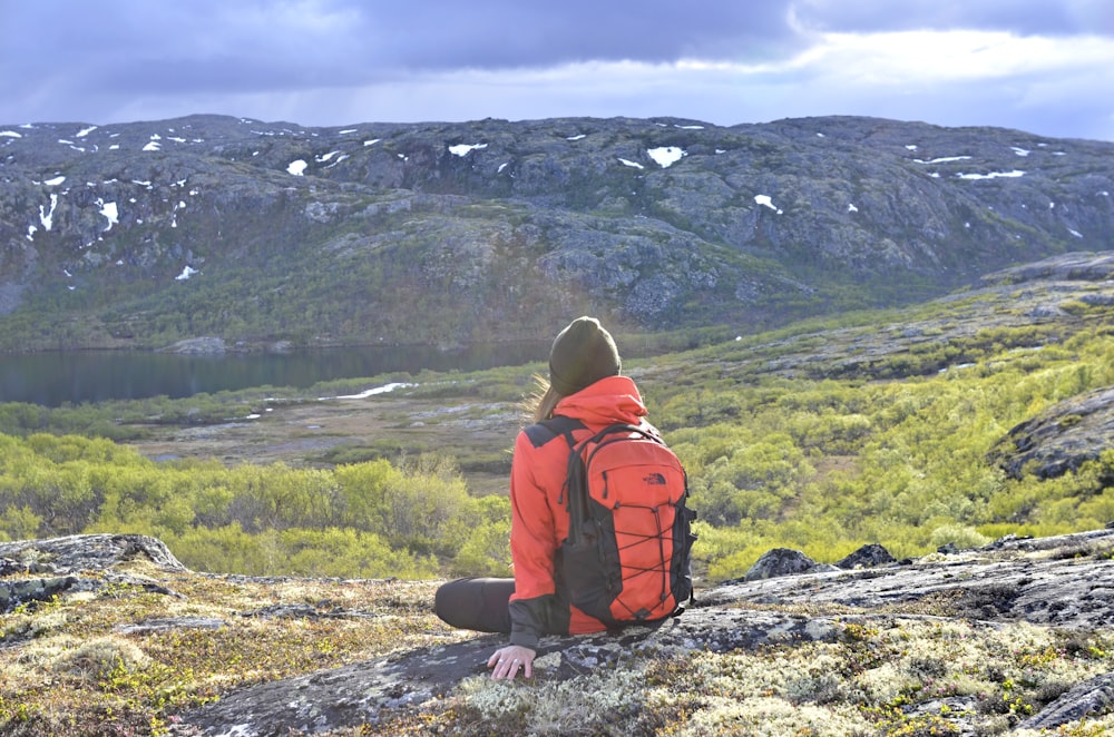 a person with a backpack sitting on a rock