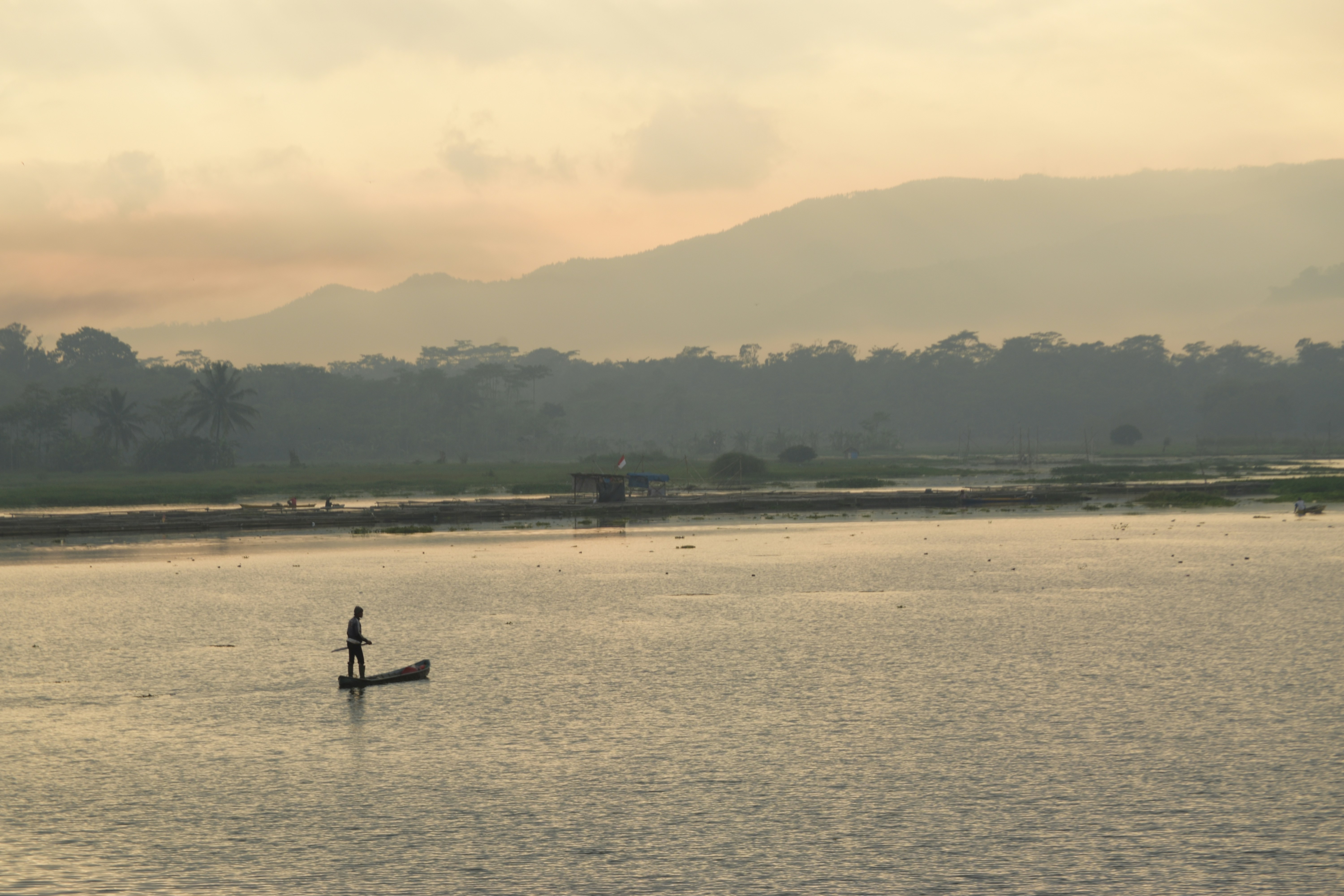 Un homme debout sur une planche à pagaie au milieu d’un lac