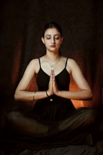 a woman sitting in a yoga position with her eyes closed