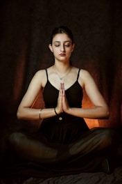 a woman sitting in a yoga position with her eyes closed