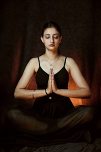 a woman sitting in a yoga position with her eyes closed