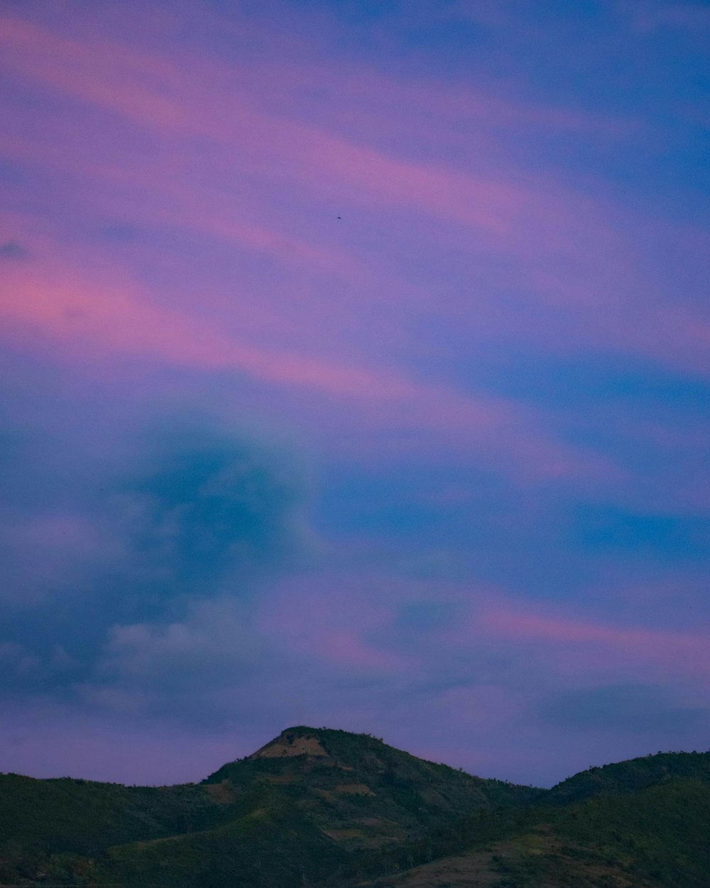 a plane flying over a mountain under a purple sky