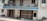 A building facade with a blue sign reading 'St. Joseph of Cluny Montessori School.' The balcony features potted plants and the entrance includes two metal gates. A green bicycle is parked near the entrance, with bricks and construction materials stacked on the side.