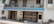 A building facade with a blue sign reading 'St. Joseph of Cluny Montessori School.' The balcony features potted plants and the entrance includes two metal gates. A green bicycle is parked near the entrance, with bricks and construction materials stacked on the side.