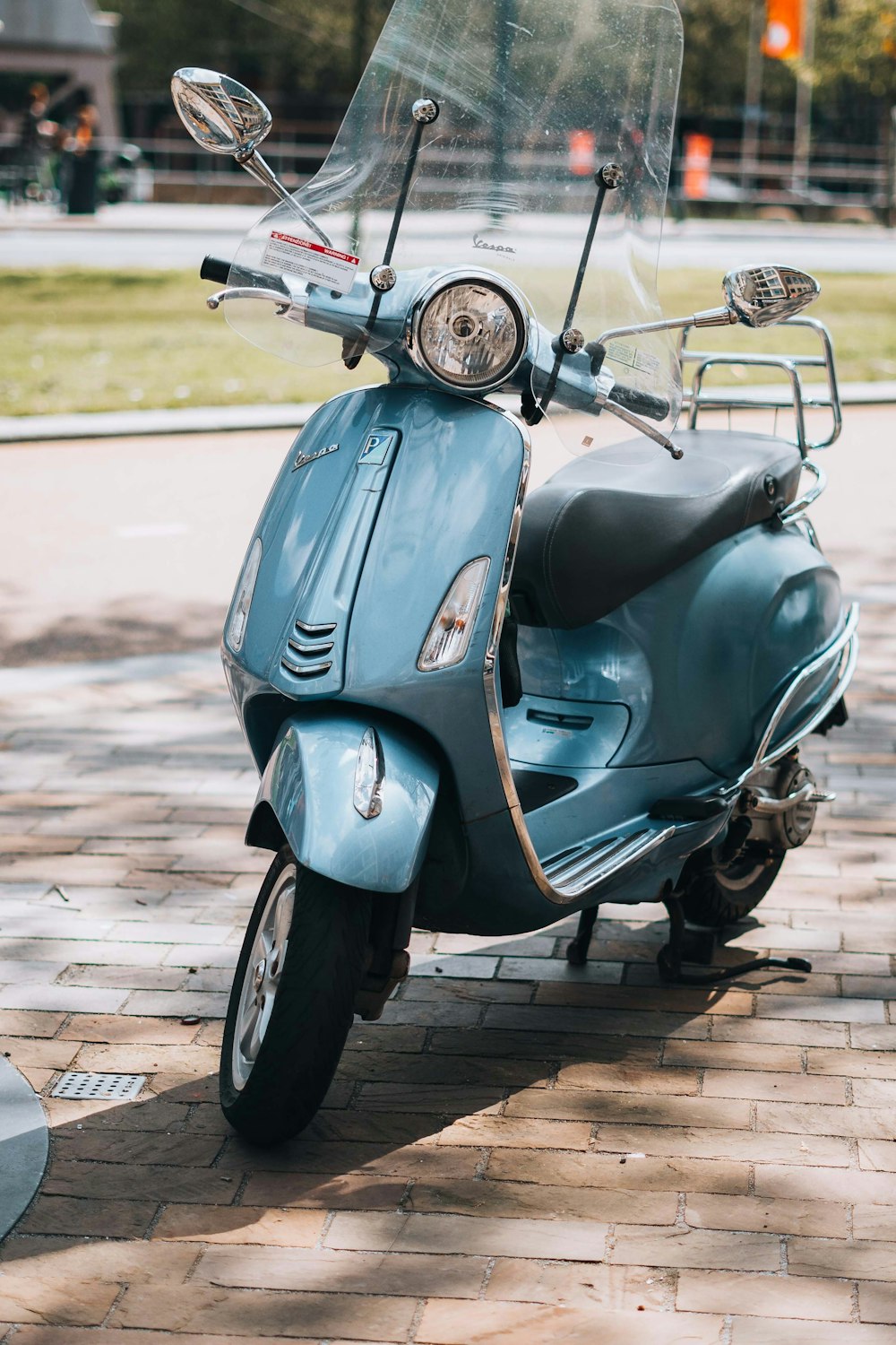 a blue scooter parked on a brick sidewalk