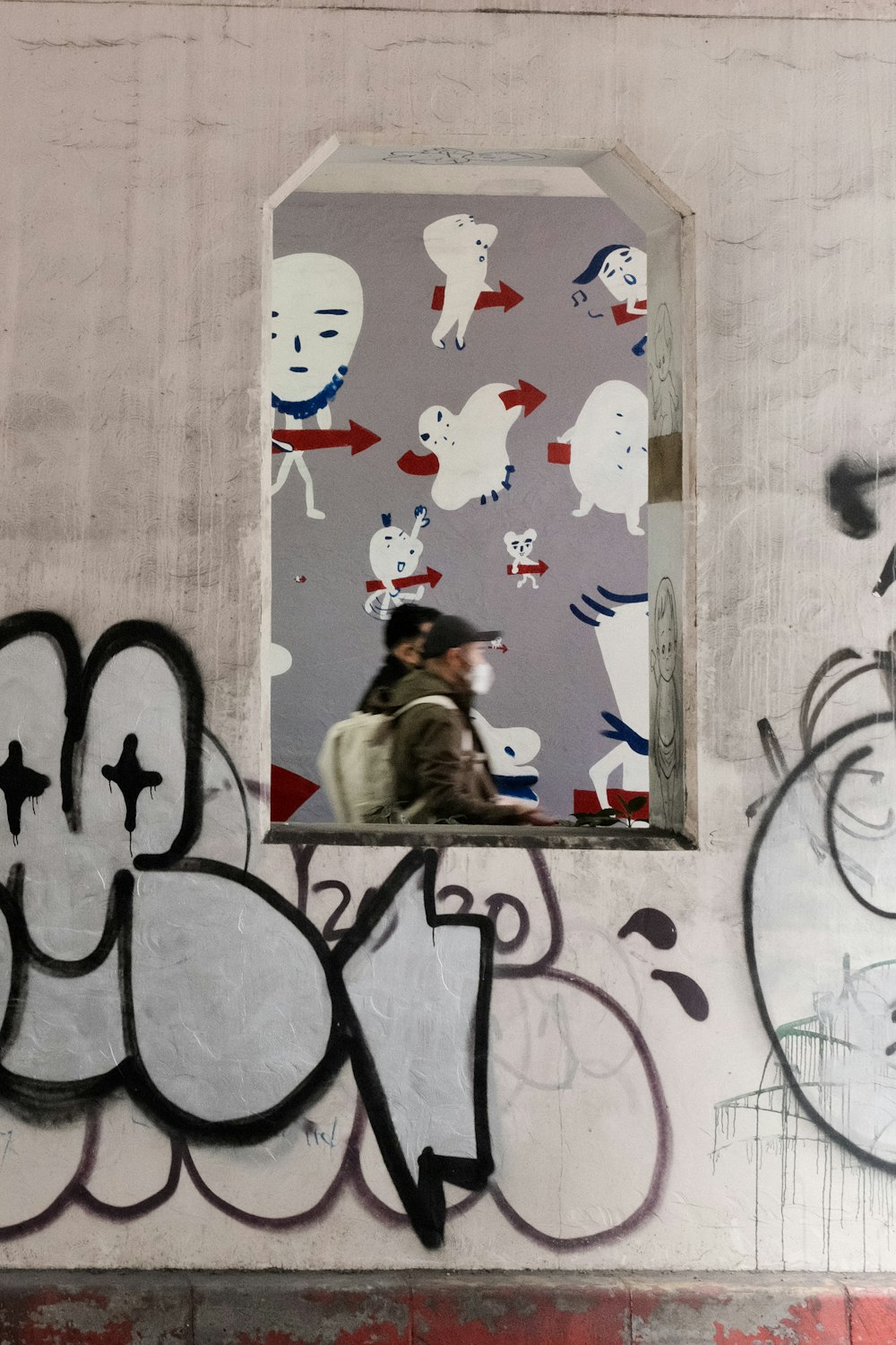 a man walking past a wall with graffiti on it