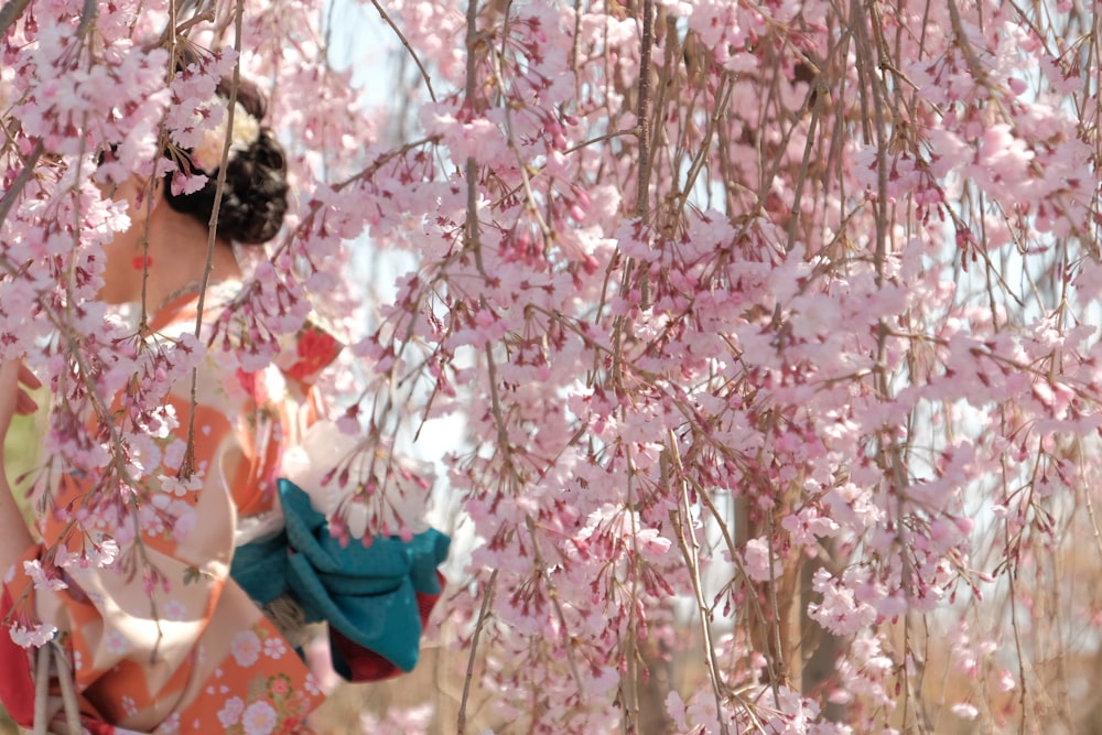 a woman in a kimono standing under a cherry blossom tree