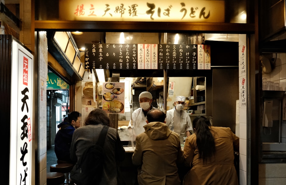 a group of people standing outside of a restaurant