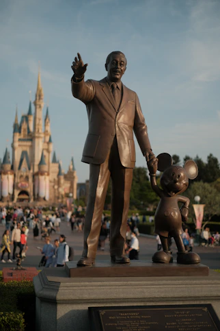 a statue of walt and mickey mouse in front of a castle