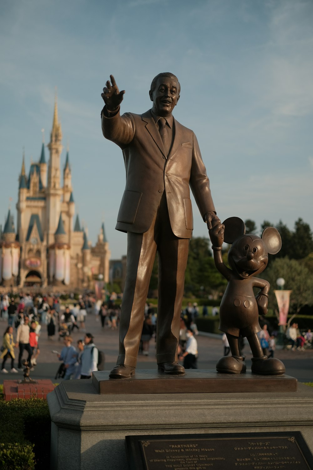 a statue of walt and mickey mouse in front of a castle