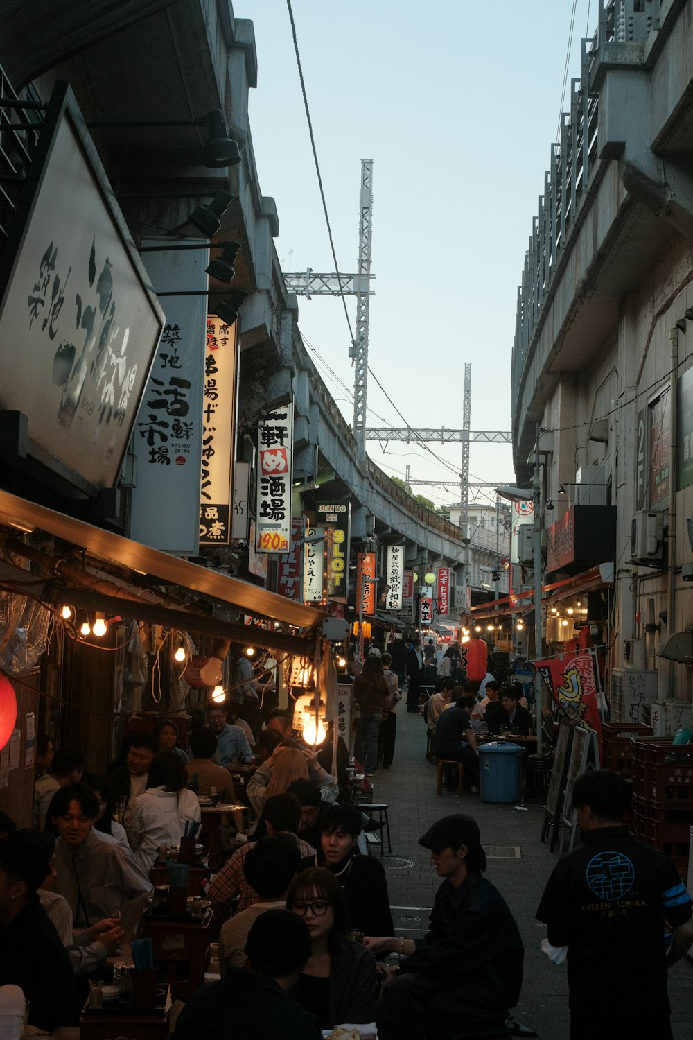 a group of people walking down a street next to tall buildings