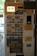 A vending machine for purchasing food tickets, featuring a user interface with photos of various meal options. Prominent instructions in both Japanese and English guide users on how to obtain and use the tickets. The machine accepts coins and notes, and different food selections are available, such as pizza and other dishes.