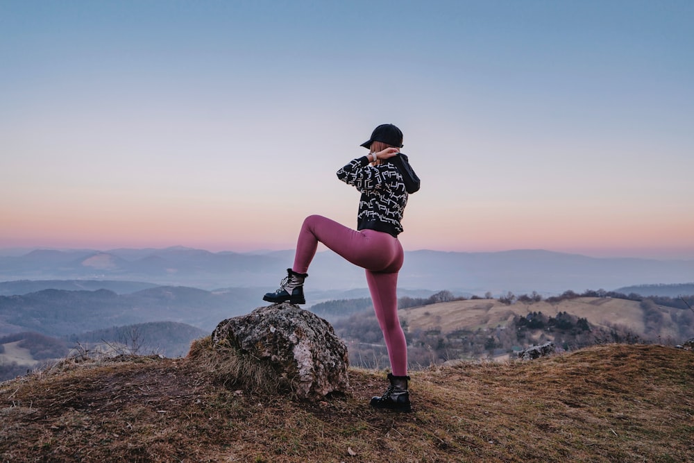 a woman in a black and white shirt and pink leggings stands on a