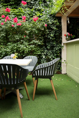 Outdoor patio featuring elegant forest green furniture surrounded by blooming flowers.