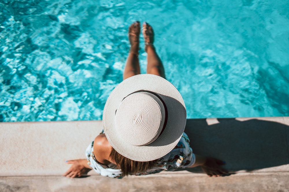 a woman in a hat is sitting by a pool